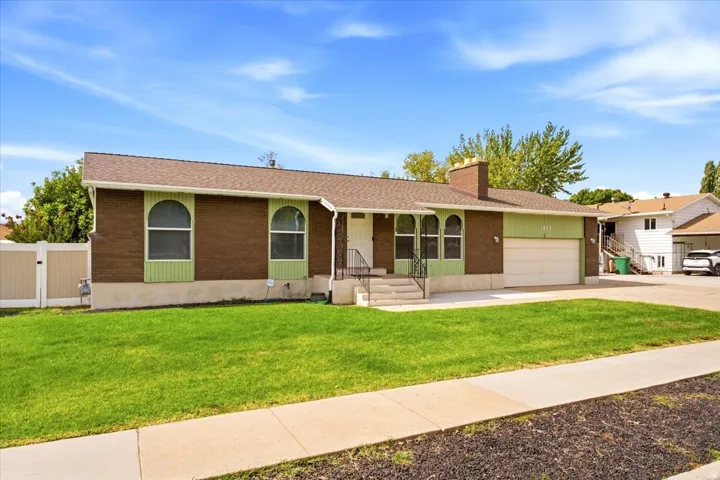 Brick and siding exterior with arched windows, attached garage, and front entrance with porch and handrail