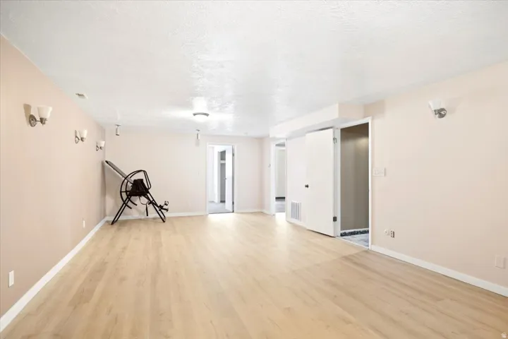 Spacious room featuring wood-finish flooring, neutral-toned walls, and recessed lighting