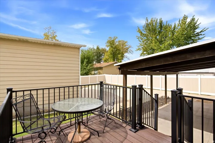Exterior deck with dark wood-finish flooring, black metal railing, and an adjacent covered outdoor structure