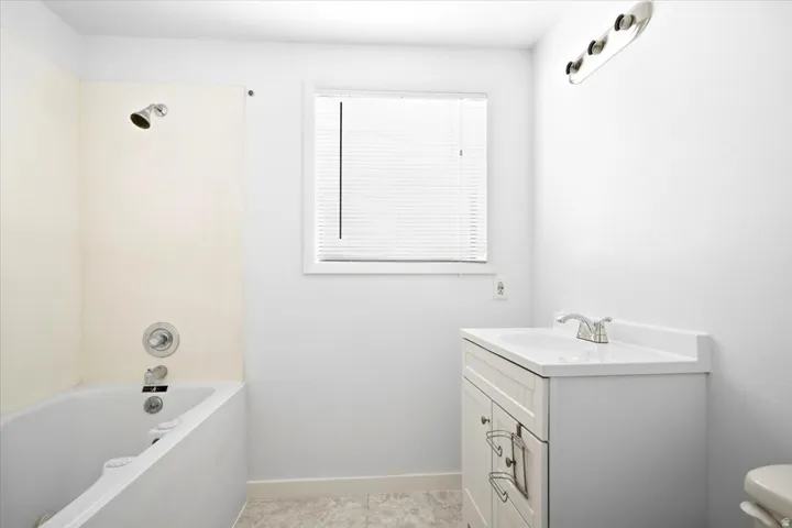 Bathroom featuring a white vanity with integrated sink, chrome faucet, and overhead bar lighting