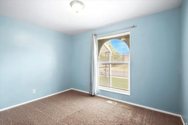 Arched window with blinds, wall-to-wall carpeting, and flush mount ceiling light fixture