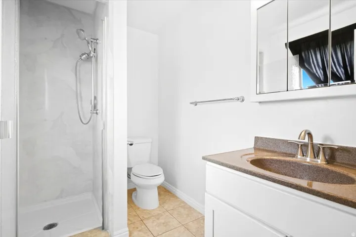 Walk-in shower with a chrome shower head and white surround