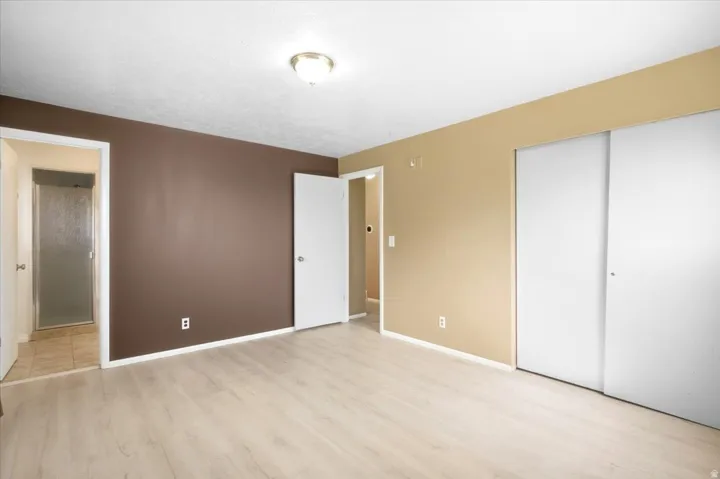 Wood-finish flooring, flush mount ceiling light, sliding closet doors, and a neutral color palette
