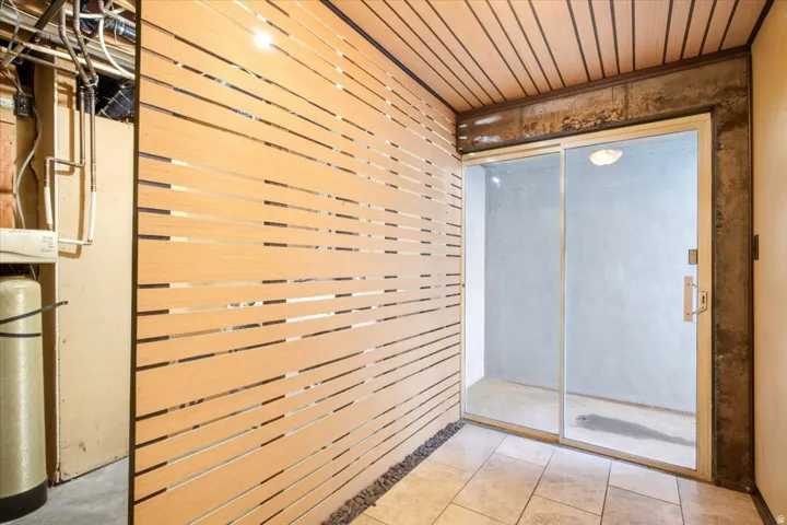 Wood-slatted wall paneling with a stone-lined base, wood-paneled ceiling, and sliding glass door