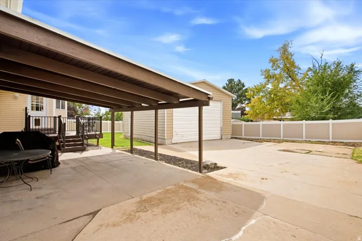 Covered patio with a concrete surface, leading to an expansive concrete driveway