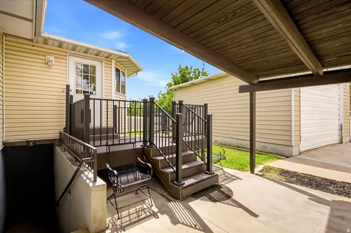 Covered exterior porch with wood-finish ceiling, vinyl siding, and wrought iron railings