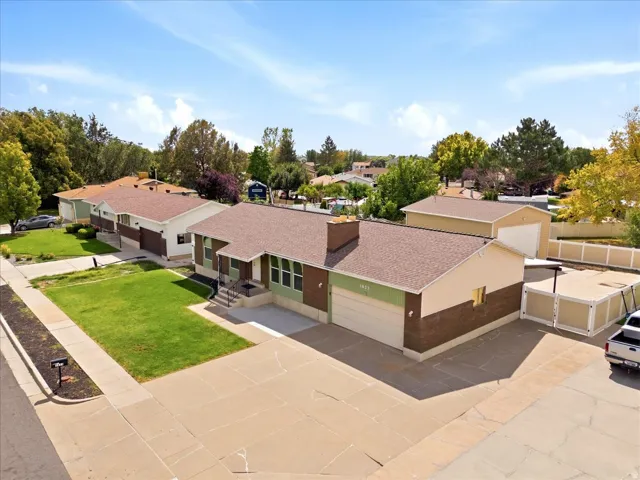 Expansive paved driveway, attached single-car garage, brick and siding exterior, front lawn, and mature trees
