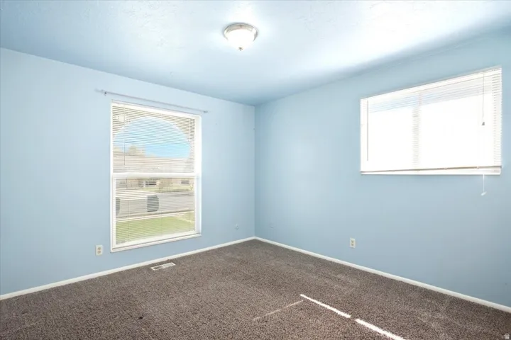 Wall-to-wall carpeting with multiple windows and an overhead light fixture
