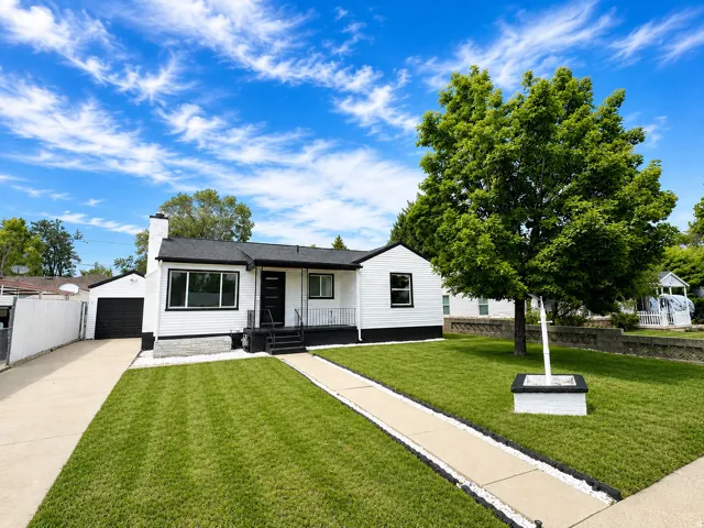 White exterior with dark trim and roof, featuring a detached garage, concrete driveway, and front walkway