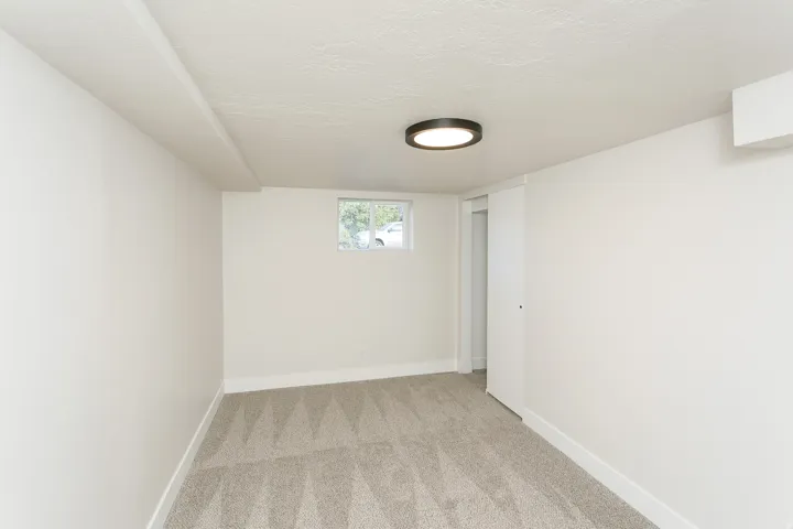 Recessed window, textured ceiling, flush mount lighting, and light gray patterned carpeting