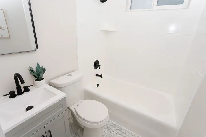 White subway-tiled shower with a built-in shelf and matte black fixtures
