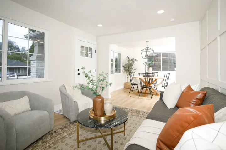 Recessed lighting, wood-finish flooring, white paneled accent wall, and a dining area with a geometric chandelier