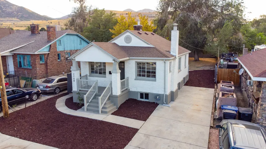 White painted brick exterior with a front porch, grey steps, and a paved driveway