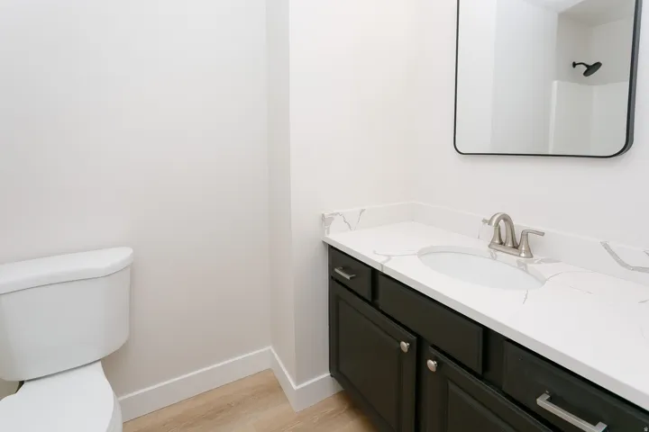 Bathroom featuring a dark wood-finish vanity with a white countertop, undermount sink, and brushed nickel fixtures