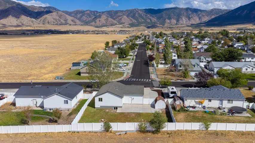 Mountain backdrop, paved street, residential neighborhood, fenced yard, detached shed