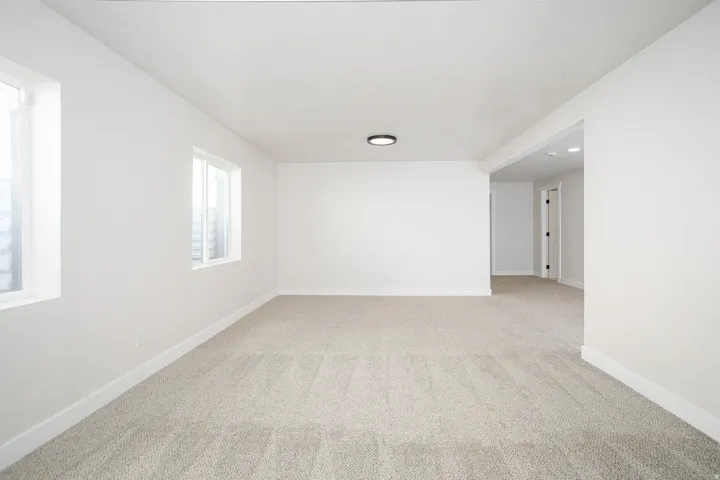 Light neutral carpet flooring, white painted walls, and a contemporary ceiling light fixture