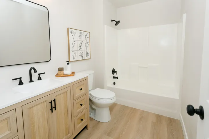 Light wood-finish flooring with a white bathtub and shower combination