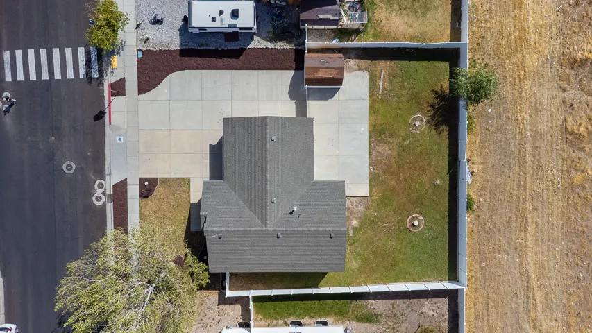 Concrete driveway with a detached shed, fenced rear yard, and an asphalt shingle roof