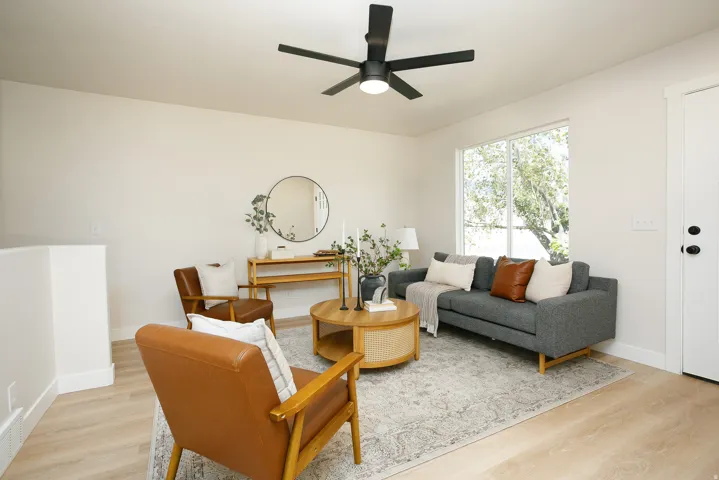Light-toned wood-finish flooring, a contemporary ceiling fan, and a large window with exterior views