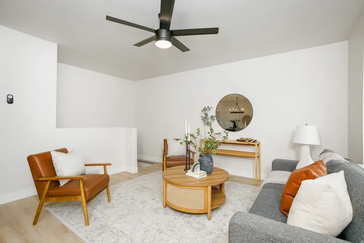 Recessed lighting, wood-finish flooring, and a modern ceiling fan in a neutral-toned living area