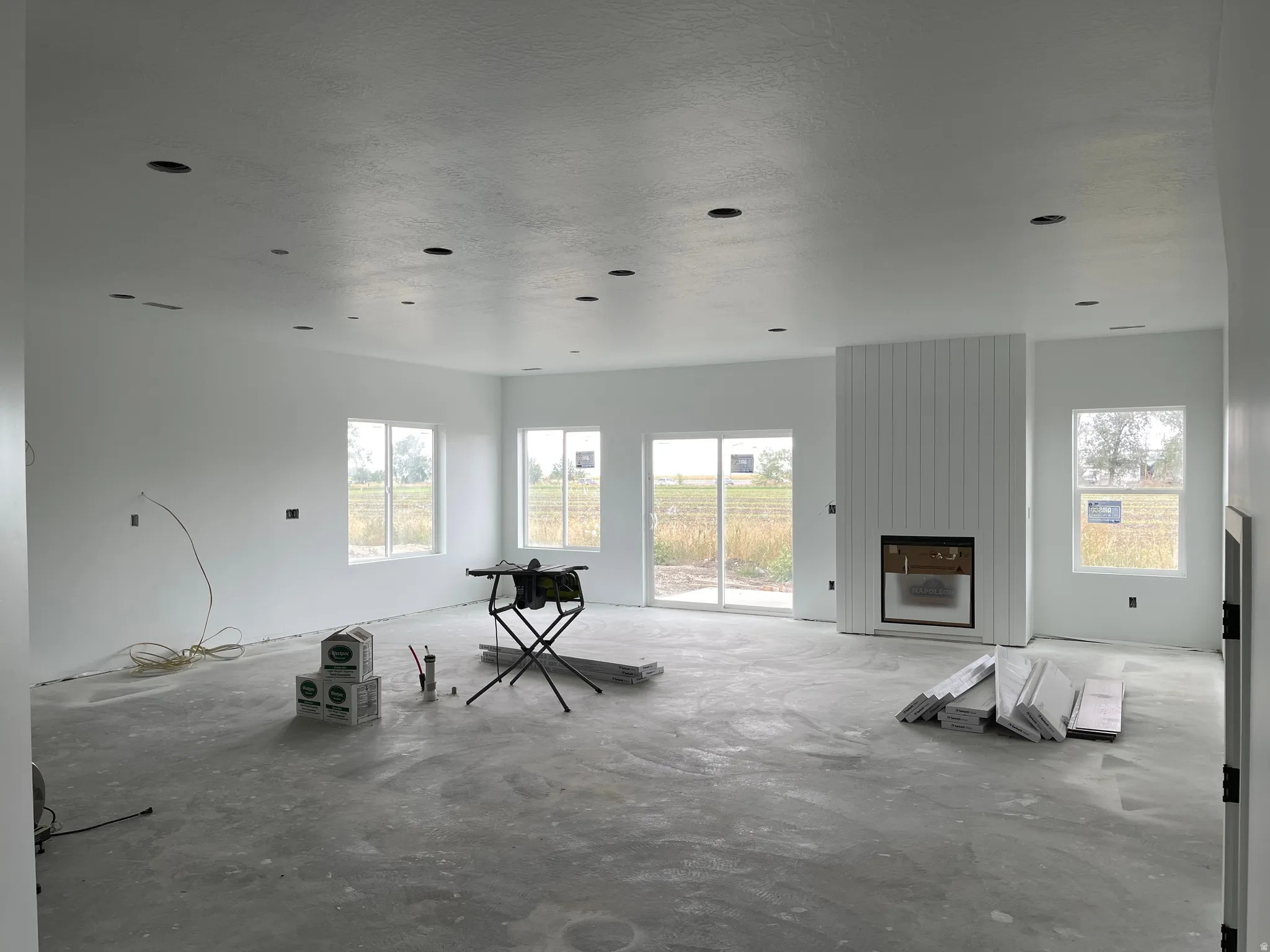 Recessed lighting throughout, multiple windows, sliding glass door, and a fireplace with vertical paneling