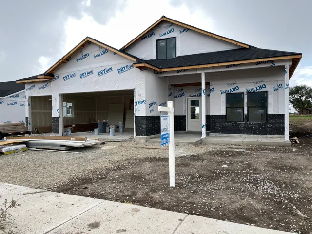 New construction framing featuring a covered entryway, attached two-car garage, and a concrete sidewalk