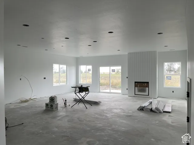 Recessed lighting throughout, multiple windows, sliding glass door, and a fireplace with vertical paneling