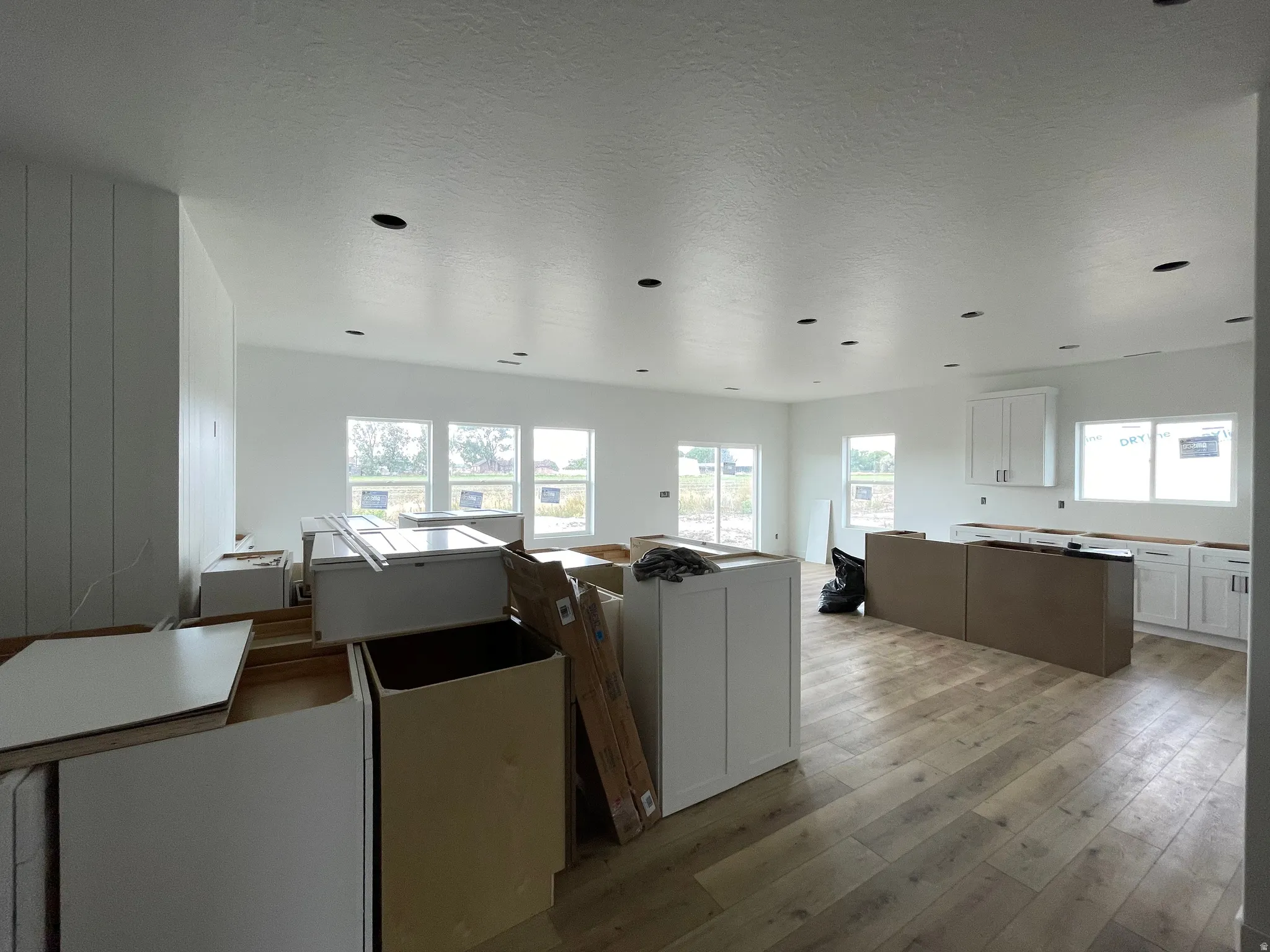Open-concept living area with wood-finish flooring, white cabinetry, recessed lighting, and a sliding glass door