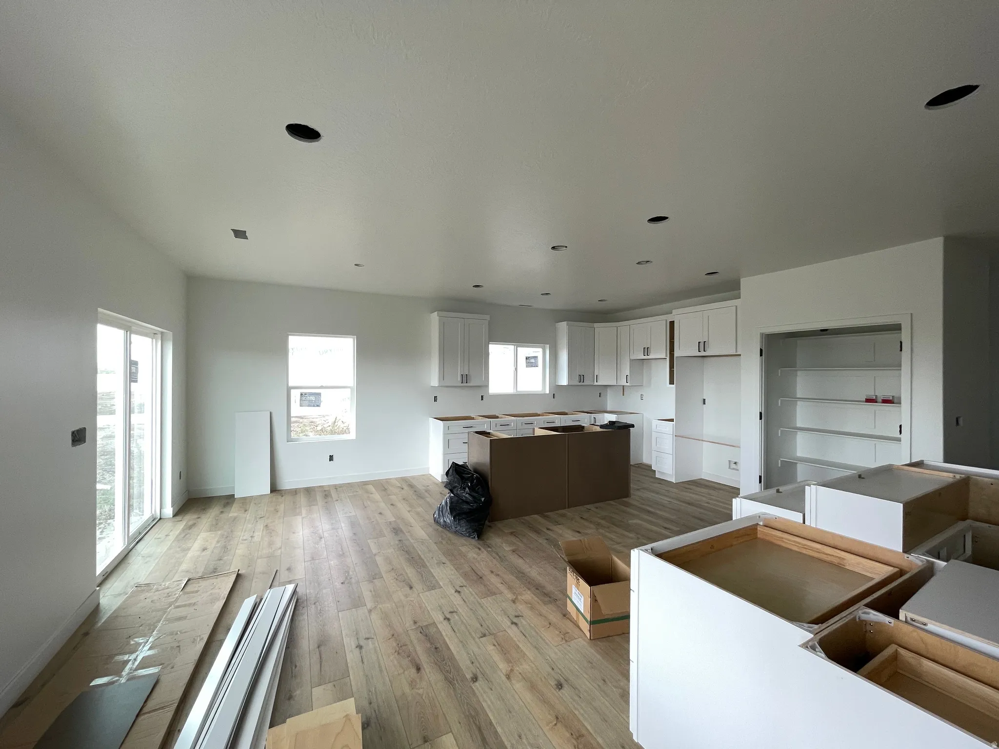 Open-concept living area with wood-finish flooring, white cabinetry, recessed lighting, and a sliding glass door