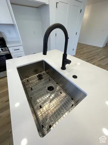 Kitchen island featuring a white quartz countertop, undermount stainless steel sink, matte black gooseneck faucet, and protective bottom sink grid