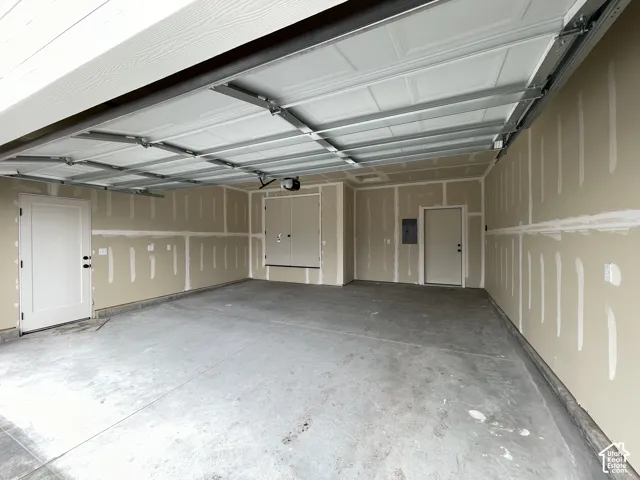 Attached garage featuring a concrete floor, sectional overhead door, premium wifi opener, side entry door, and finished drywall