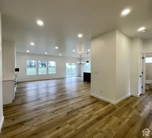Open-concept interior featuring wood-finish flooring, recessed lighting, expansive multi-pane windows, and a central kitchen island