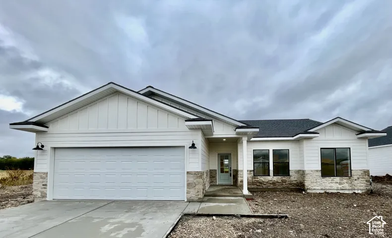 Single-level exterior featuring horizontal siding, natural stone accents, a multi-car garage, and a covered front entry