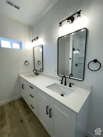 Double-vanity with white shaker cabinetry, white solid-surface countertop, rectangular undermount sinks, matte black widespread faucets, and rounded rectangular mirrors with matte black frames