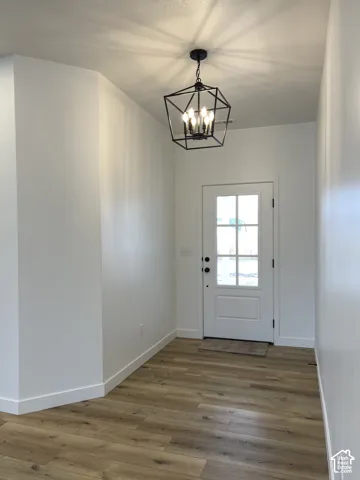 Entryway featuring wood-finish flooring, a geometric matte black pendant light fixture, and a white single-lite door with decorative glass panes