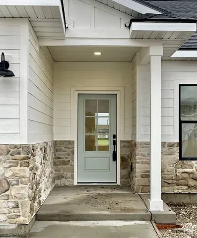Covered entryway featuring stone veneer siding, horizontal lap siding, a six-pane glass front door, and a black metal exterior light fixture