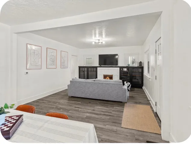 Living area featuring wood-finish flooring, a white brick fireplace, built-in cabinetry, and white trim