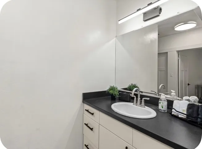 Integrated vanity with a dark countertop and undermount sink, brushed nickel faucet, and overhead bar lighting fixture