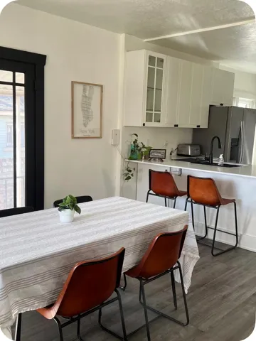 White cabinetry, stainless steel refrigerator, black matte sink, black matte faucet, and wood-finish flooring