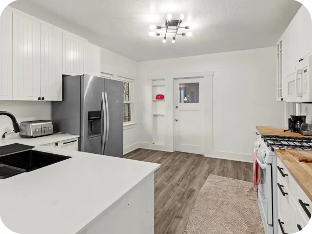 White cabinetry with black hardware, wood-finish flooring, white countertops, built-in shelving, and a glass-paneled door