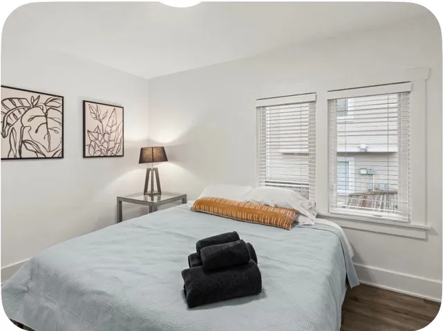 Dual windows with blinds, wood-finish flooring, and white walls