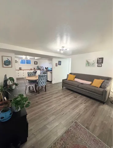 Open-concept living space featuring wood-finish flooring, recessed lighting, and a kitchen with white cabinetry