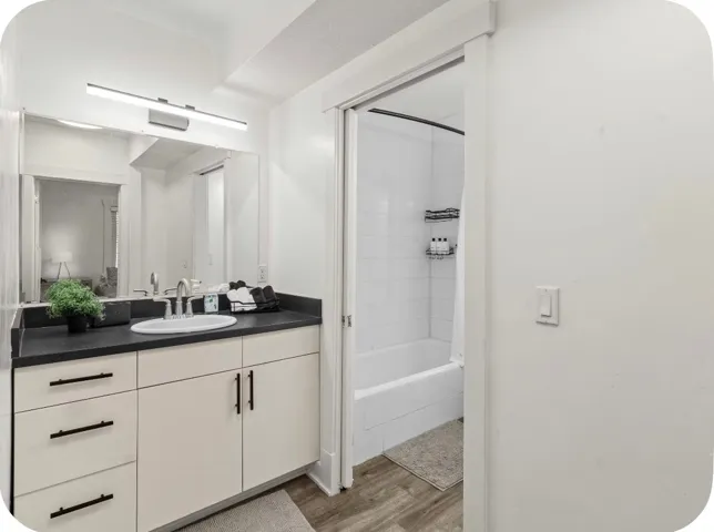 Light-toned vanity with black hardware, dark countertop, and integrated sink
