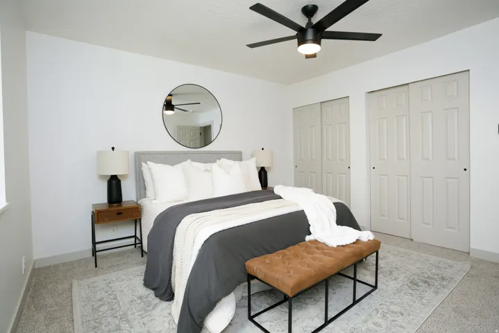 Recessed window, ceiling fan with integrated lighting, two sets of sliding panel closet doors, and neutral wall-to-wall carpeting