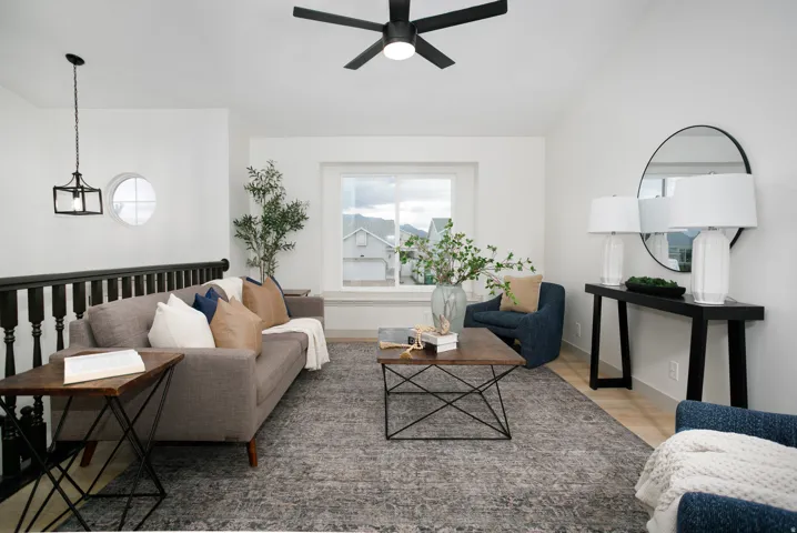 Spacious living area featuring a vaulted ceiling with a ceiling fan, a window seat, and wood-finish flooring