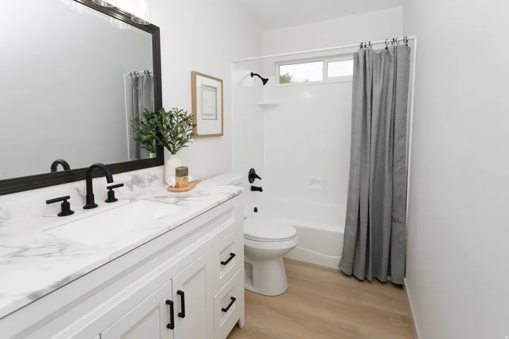 White vanity with black hardware, integrated sink, and stone-finish countertop
