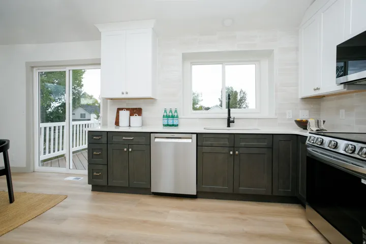 Kitchen featuring two-tone cabinetry, stainless steel appliances, a sliding glass door, and wood-finish flooring