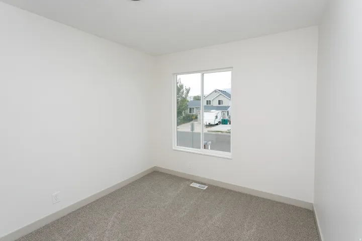 Clean white walls with a single window, recessed lighting, and grey carpeting