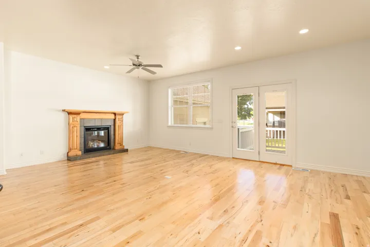 Hardwood flooring, fireplace with wood mantel and tile surround, ceiling fan, recessed lighting, and patio doors