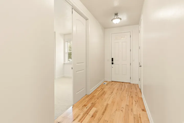 Wood-finish flooring, white paneled door with transom window, flush mount ceiling light, and white walls